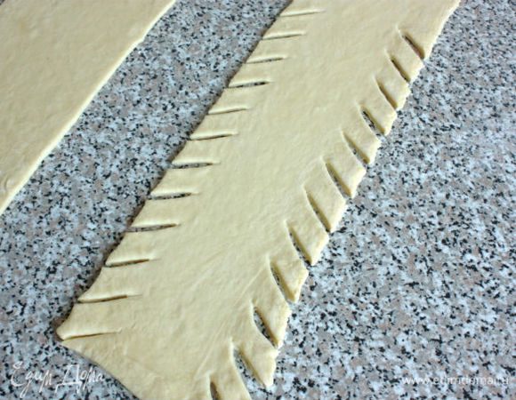 С краёв к центру под углом нарезать тесто полосками в 2 см шириной и 4 см длиной.