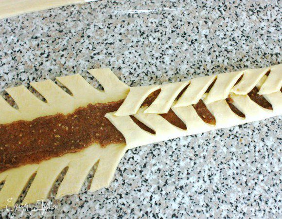  По всей длине равномерно выложить ложкой начинку шириной 4 см. Сложить поочередно полоски над начинкой слегка внахлёст.