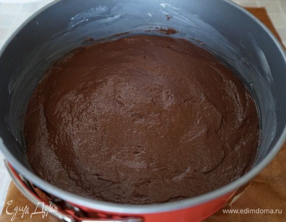 Дно разъемной формы выстелить пергаментом, смазать боковые стороны сливочным маслом. Выложить тесто, разровнять и поставить выпекаться в духовку на 20 минут. После выпечки, корж из формы не вынимать, оставить для остывания. Температуру в духовке понизить до 160 градусов. 