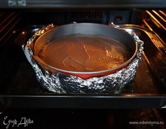 В духовке у нас уже 160 градусов. Поставить в духовку глубокий противень с горячей водой. Дно и боковые стенки разъемной формы, в которой находится корж, очень тщательно обернуть фольгой в несколько слоев, чтобы внутрь не могла попасть вода. Отнестись к этому шагу со всей тщательностью и вниманием! Выложить на корж сырный крем и отправить форму в духовку на водяную баню. Выпекайте 40-50 минут, следите по своей духовке. По краям торт должен схватиться, стать плотным, а серединка немного дрожать. Оставить форму до полного остывания в приоткрытой духовке. Торт в принципе готов.