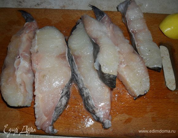 Сначала подготовим рыбу. Хорошо помоем под проточной водой, высушим бумажным полотенцем и нарежем на порционные куски. У меня в ингредиентах написано филе, но я использовала вместе с хребетиком. Посолим, поперчим и сбрызнув соком половины лимона оставим на некоторое время, чтоб рыба пропиталась специями. Можно посыпать и другими специями по вкусу. 