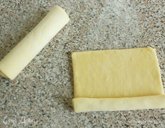 Готовое тесто разморозьте. Каждую пластину смажьте с одной стороны взбитым яйцом (или растопленным маслом) и скатайте в плотный рулет, смазанной стороной внутрь.
