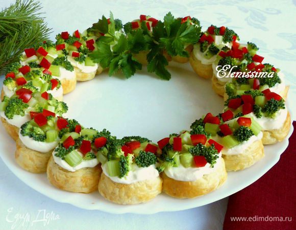 Поочередно разложите брокколи, кусочки сельдерея, затем перец. Веточками сельдерея с листочками украсьте венок, имитируя бант.
В центр можно поместить низкую толстую свечу-гости не сразу сообразят, что это не просто декор, а настоящая еда.