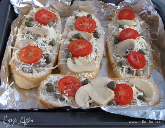 Посыпать багеты тертым сыром, украсить помидорами, грибами, каперсами. Отправить в духовку, разогретую до 200 град, на 20 минут до зарумянивания сыра.