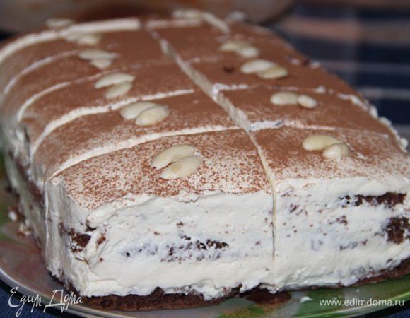 Накрыть вторым коржом, выложить еще половину оставшегося креса , накрыть третьим и смазать оставшимся кремом. Поставить на 3 часа в холодильник. Перед подачей удалить бортики, посыпать порошком какао и разрезать на 16 частей. Украсить лепестками миндаля.