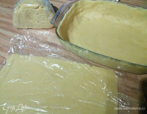 Меньшую часть теста раскатываем в тонкий пласт, завернём в плёнку, также накрываем форму с тестом плёнкой и ставим в холодильник. 