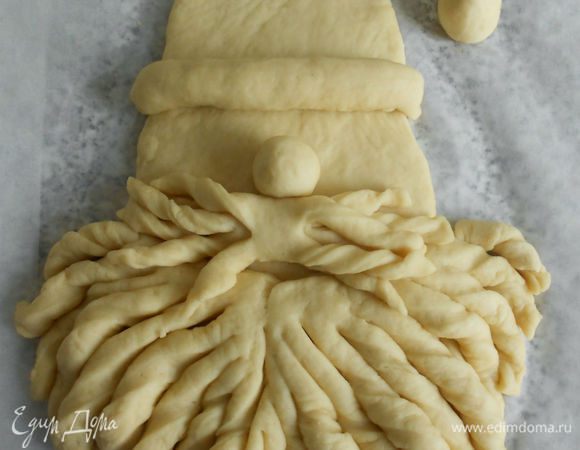 Приложить на «лицо» и закрутить полоски в локоны. При желании нижнюю часть бороды также можно предварительно нарезать и закрутить, тогда борода будет пышнее.

 Из оставшегося теста сделать усы, нос, опушку шапки и помпон. Для усов тесто раскатать в тонкий прямоугольник, с боков к середине нарезать тонкими полосками, скрутить в рулетик и поместить его выше бороды. (Усы можно было и поинтереснее придумать...Поздно сообразила.) Над усами положить небольшой шарик теста-нос.
