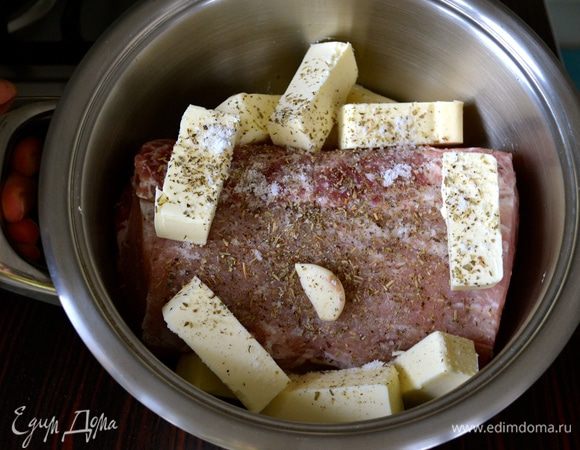 Свиную вырезку положить в небольшую кастрюлю с двойным дном. Кусок мяса должен занять, практически, весь объем кастрюли. Положить зубчики чеснока, нарезанное сливочное масло, посолить, поперчить по вкусу и посыпать смесью ароматных трав (на Ваш вкус).