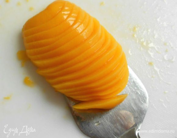 С помощью хлебного ножа или лопатки для торта перенести 7 половинок персиков на пирог, стараясь придать им вытянутую форму лепестка.