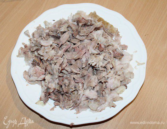 Остывшую рульку разобрать руками, отделить мясо от костей и кожи. Удалить лишний жир, темные прожилки.  Мелко нарезать мясо. 