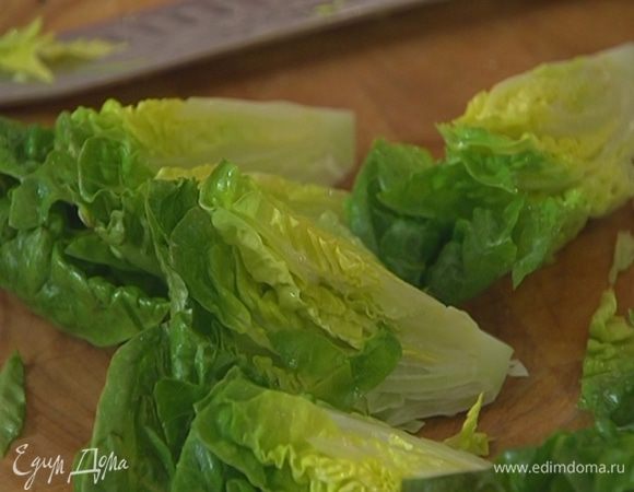 Салат романо разрезать на 4 части, выложить на большую тарелку и полить половиной заправки.