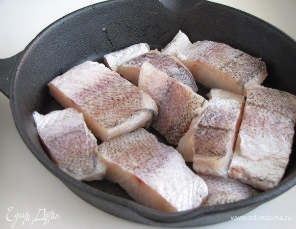 Филе рыбы нарезать кусочками, обсушить бумажным полотенцем. Выложить в чугунную сковороду или огнеупорную форму.