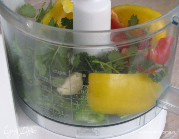 Перец сладкий и острый очистить от семечек, нарезать произвольными кусочками, выложить в чашу блендера. Добавить очищенный лук, зубчики чеснока, базилик и кинзу. Все измельчить не слишком мелко.