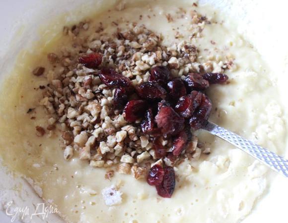 Всыпаем половину орехов и клюквы, еще раз быстро перемешаем ...