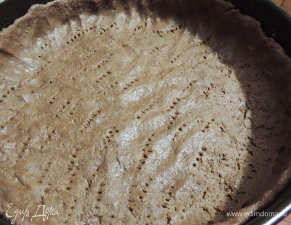 Распределяем тесто по форме диаметром 26см, дно которой выстелено бумагой, бортики можно смазать маргарином или растительным маслом. Формируем из теста небольшие бортики. Дно накалываем вилкой.