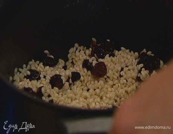 В глубокой кастрюле растопить 1 ст. ложку сливочного масла, всыпать рис и дать ему пропитаться маслом 1–2 минуты, затем добавить изюм, перемешать и прогреть еще немного.