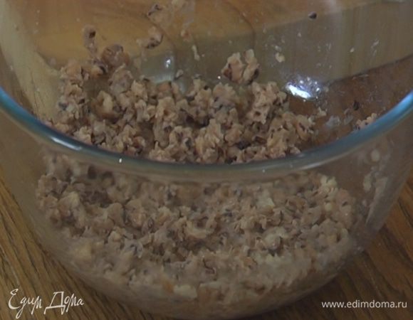 Слить жидкость из фасоли и размять ее толкушкой, так чтобы остались небольшие кусочки.