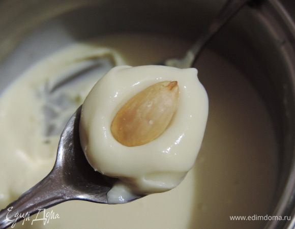 Когда смесь загустеет, набираем ее чайной ложечкой, сверху вдавливаем очищенный орешек миндаля.