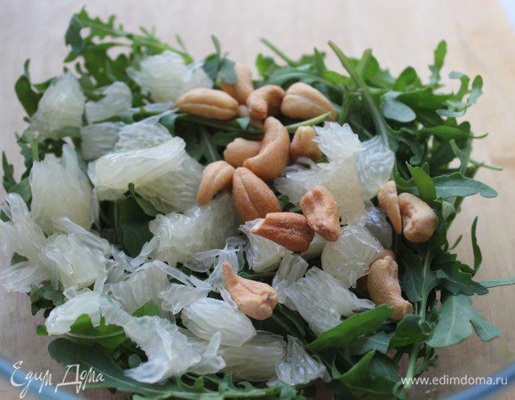 Смешать в глубокой чашке помытую руколу, помело и орехи. Заправить соусом.
Выложить на тарелку кольца помидор внахлест, по центру выложить горкой салат и  украсить раковыми шейками. 