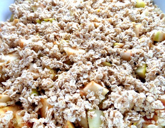 Яблоки раскладываем по дну смазанной керамической формы (27 см),сверху засыпаем крошкой.