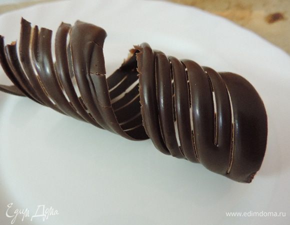 Я торт украсила шоколадной спиралькой. 
Чтобы сделать ее, наносим растопленный черный шоколад на длинную ленту из бумаги для выпечки. Когда шоколад уже не течет, но все еще остается пластичным, аккуратно наматываем ленту по спирали на узкий цилиндрический предмет, например рулон пищевой пленки. Закрепляем края скотчем. Отправляем в холодильник до полного застывания. Затем аккуратно снимаем ленту с рулона и очень осторожно вытягиваем бумагу за кончик из получившегося завитка. Чтоб его поверхность была рельефной, перед наматыванием ленты на рулон можно сделать полосочки при помощи вилки или кондитерского гребешка. 