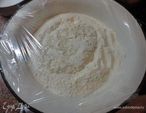 Муку просеять в миску. Сделать углубление. Отдельно в 100 г теплого молока развести дрожжи и добавить 3–4 ст. л. муки. Опару вылить в углубление, сделанное в муке, и посыпать мукой. Тесто закрыть пленкой и поставить на 30 минут в теплое место.