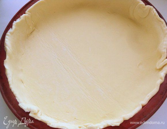 Пласт теста разморозить, раскатать толщиной 5 мм и вырезать круг размером больше диаметра формы для выпечки на 2 см. У меня форма силиконовая (Ф-24 см), поэтому ничем ее не смазывала. Выложить тесто в форму, сформировать бортики.