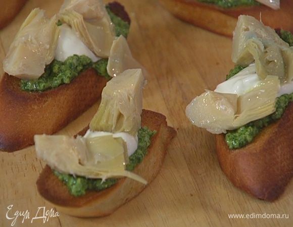 Смазать подсушенный хлеб соусом песто, сверху выложить понемногу сметаны и кусочки артишоков.
