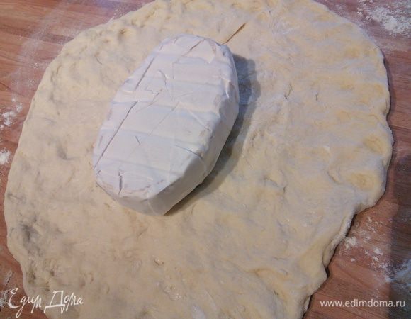 В любом случае выложите тесто на посыпанную мукой рабочую поверхность. Распластайте его руками. Выложите сыр ( он должен быть продолговато-овальной формы). 