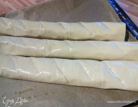 Скатать в рулет, тщательно подгибая края. Таким образом приготовить три рулета, выложить на противень. Смазать их поверхности маслом и каждые 3-4 см. сделать легкие надрезы острым ножом. 