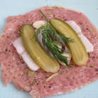 Положить на мясо по кусочку сала, 1-2 пластика огурца, чеснок и веточку укропа.