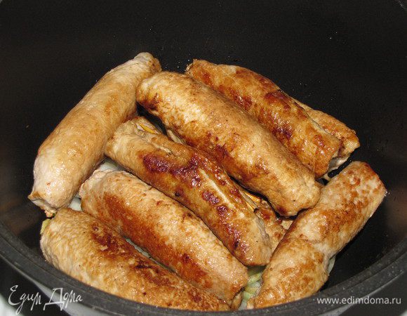 Репчатый лук почистить, нарезать кольцами и выложить на дно сотейника. На лук положить рулетики.