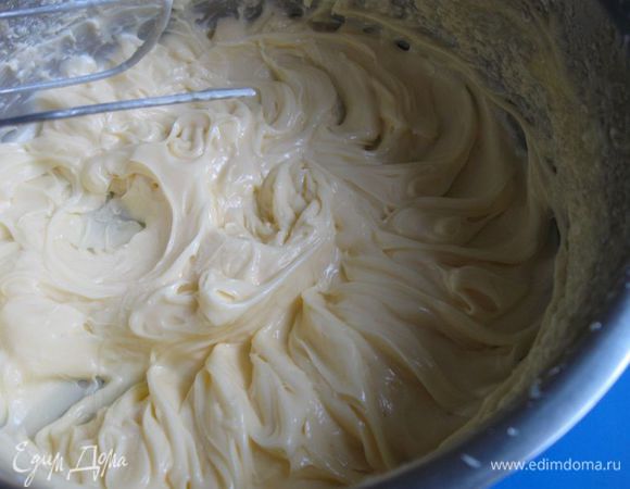 Масло и ванилин (можно заменить ванильным сахаром – 1 пакетик) взбить миксером на максимальной скорости в течение  6 – 7 минут до светлого цвета. Добавлять понемногу сироп, перемешивать миксером. 
