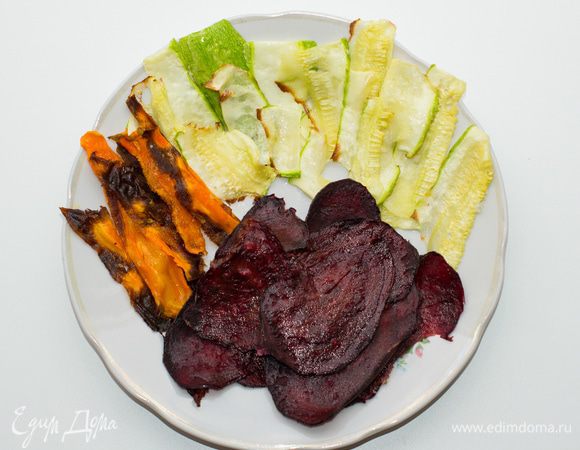 Приготовить овощные чипсы: свеклу, морковь, цукини тонко порезать, уложить на противень, смазать растительным маслом при помощи кисти (чуть-чуть). Посыпать морской солью.
Подсушить 3-4 мин. в духовке при 230 градусах.