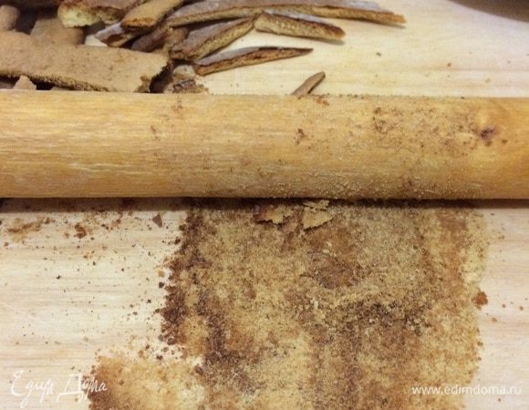 Из обрезков сделать обсыпку, для этого измельчить их скалкой. Смазать коржи кремом, примерно 3–4 ст. л. крема на каждый корж.