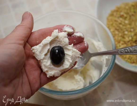 Каждую виноградину облепить сырной массой, для этого ложкой на ладошку выкладываем сыр, приминаем его в лепешку, кладём в середину виноград. Скатываем в шарик. Обвалять в фисташках.