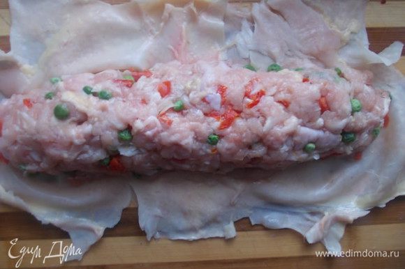 Разравниваем кожу курицы на столе и формируем колбаску,плотно ее укладывая.