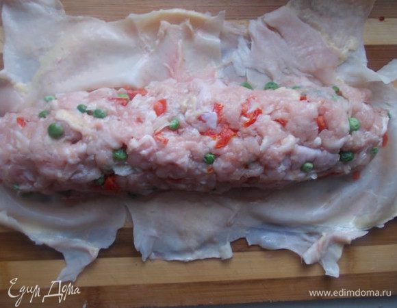 Разравниваем кожу курицы на столе и формируем колбаску,плотно ее укладывая.