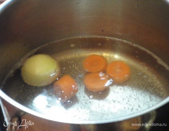 В широкую кастрюлю поместить луковицу и нарезанную крупными кусочками морковь и залить литром холодной воды. Варить 10-15 минут.