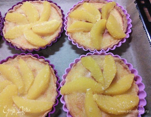 Тарталетки достанем из духовки, выложим дольками апельсина и запекаем ещё 10-15 мин. 
