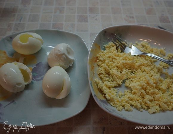 Разморозить тесто. Поставить вариться 4 яйца в подсоленную воду.  Яйца охладить, почистить. Разрезать белки до желтка, достать желтки.