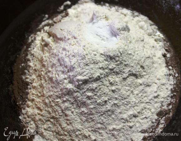 Добавляем просеянную  муку, какао и в последнюю очередь соду. 
Все быстро перемешиваем до однородной консистенции и сразу же выливаем на большой застеленный бумагой для выпечки противень. 