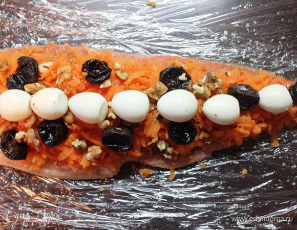 Положить на пищевую пленку (несколько слоев пленки внахлест) одно филе кожей вниз, равномерно распределить по всей поверхности морковь, затем выложить чернослив,  яйца по центру (можно заменить куриными, разрезав их пополам). 
Посыпать сверху крупно порубленными орехами.

