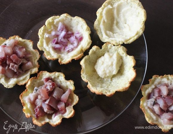 Готовые корзинки остужаем и формируем салатик. Корзинки смазываем соусом, затем выкладываем слой лука и сельди, на них — слой моркови, хорошенько промазываем соусом.