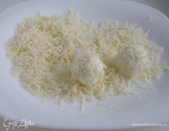 Влажными руками сформировать из феты шарики, обвалять их в тертом сыре.