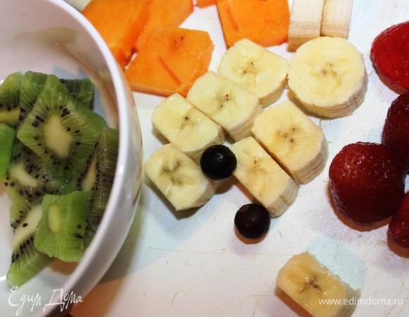 Очищаем и нарезаем фрукты желаемого размера и формы, учитывая объем ваших форм (бокалов, креманок и т.д.). 
Несмотря на вышеописанные свойства киви, мне чересчур хотелось видеть его в своем десерте (очень уж у него новогодний цвет), поэтому я предварительно опустила нарезанные кусочки в кипяток на несколько секунд, а затем промыла их в холодной воде. Это снизило кислотность киви.