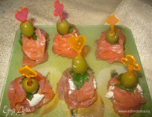 На каждый ломтик рыбы кладем по 1 столовой ложке творожной массы и сворачиваем в рулетик. 
На шпажку накалываем оливку, петрушку и рулетик.
Приятного аппетита!