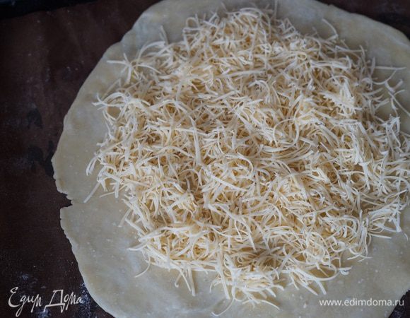 Сыр (у меня эмменталь)  натереть на мелкой или средней терке (можно грюер, ярлсберг).
Достаем тесто из холодильника. Перекладываем его на противень. 
Собираем галету. В центр галеты слоями выкладываем начинку: натертый сыр, затем лук, сверху тыкву, оставляя свободными края теста по 5 см. 