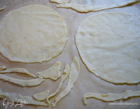 Противень немного прогреть в духовке, застелить фольгой, выложить круги теста на противень, проколоть вилкой. Рядом выложить обрезки теста.
Выпекать коржи 8-10 мин., дать им хорошенько подрумяниться.
