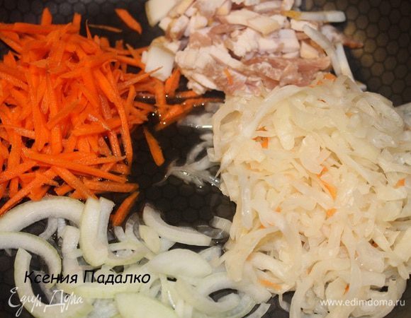 В сковороду выложить капусту, 2 пластинки бекона, морковь, нарезанную соломкой, лук, нарезанный полукольцами и масло. Обжарить на среднем огне, до слегка золотистого цвета.